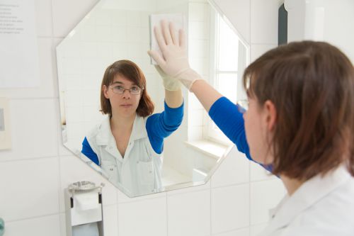 Frau schaut in den Spiegel und reinigt den Spiegel © Richard Tanzer