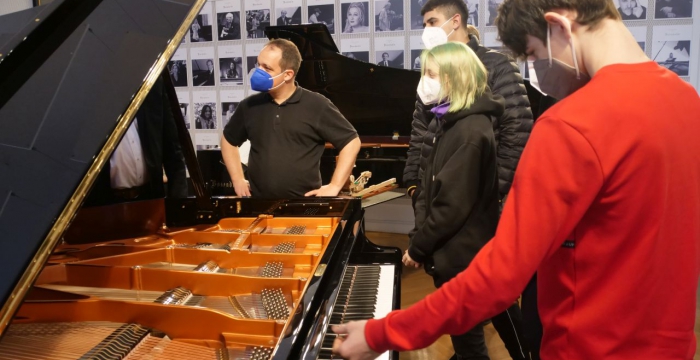 Lehrlinge mit Maske vor einem Klavierflügel im Bösendorfer Salon © Jugend am Werk