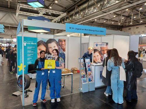 Zwei Lehrlinge halten vor dem Stand von Jugend am Werk die Auszeichnung Best of BeSt 2025 in die Höhe © Jugend am Werk