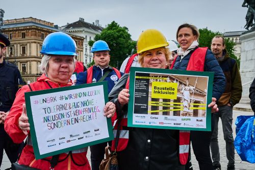 Zwei Selbstvertreter:innen halten ihre Plakate mit Forderungen in die Höhe © C. Mavric