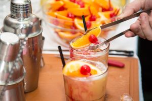 Orangenscheibe wird auf einem Cocktailglas platziert © APA-Fotoservice/Krisztian Juhasz