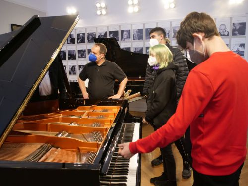 Lehrlinge mit Maske vor einem Klavierflügel im Bösendorfer Salon © Jugend am Werk